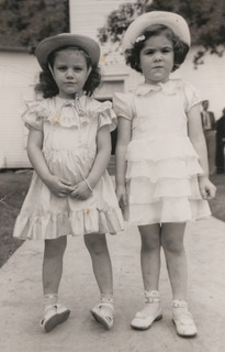 Two girls in matching dresses and hats.
