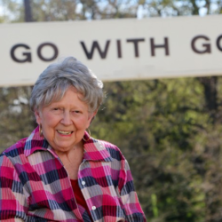 Smiling elderly woman in checked shirt.